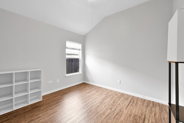 empty room with baseboards, wood finished floors, and lofted ceiling