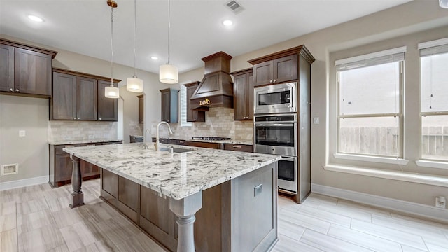 kitchen featuring a sink, stainless steel appliances, baseboards, tasteful backsplash, and light stone countertops