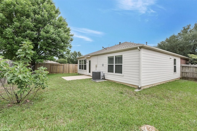 back of house with a fenced backyard, a patio, a lawn, and central AC