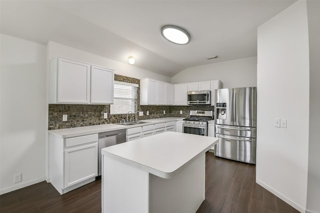kitchen featuring backsplash, vaulted ceiling, dark wood finished floors, a sink, and stainless steel appliances