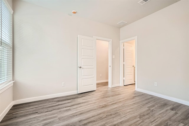 unfurnished room with light wood-style floors, baseboards, and visible vents