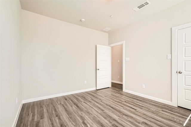 spare room with baseboards, visible vents, and wood finished floors