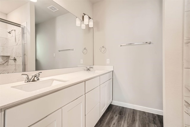 bathroom with wood finished floors, visible vents, a sink, and a stall shower