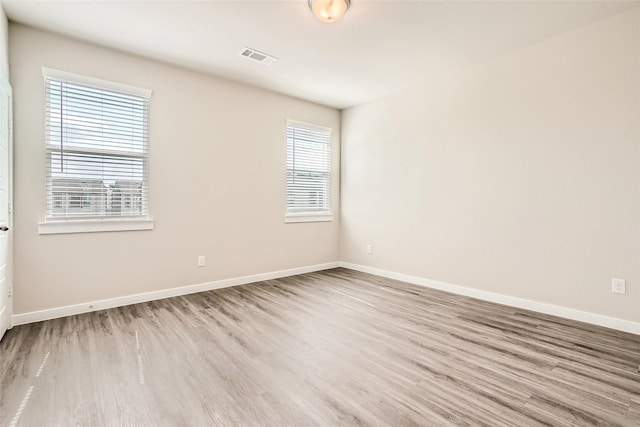 unfurnished room with baseboards, wood finished floors, and visible vents
