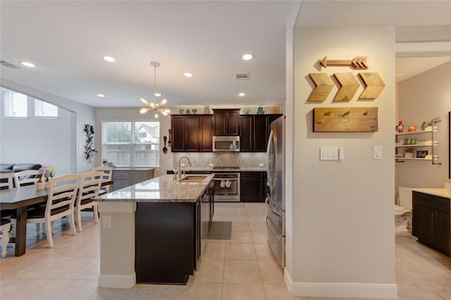 kitchen featuring visible vents, light stone countertops, tasteful backsplash, a sink, and appliances with stainless steel finishes