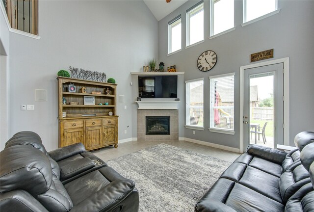 living area featuring light tile patterned floors, high vaulted ceiling, baseboards, and a tile fireplace
