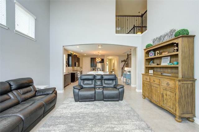 living room featuring baseboards, arched walkways, a high ceiling, and light tile patterned flooring