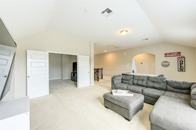 living room with visible vents, arched walkways, lofted ceiling, and light carpet