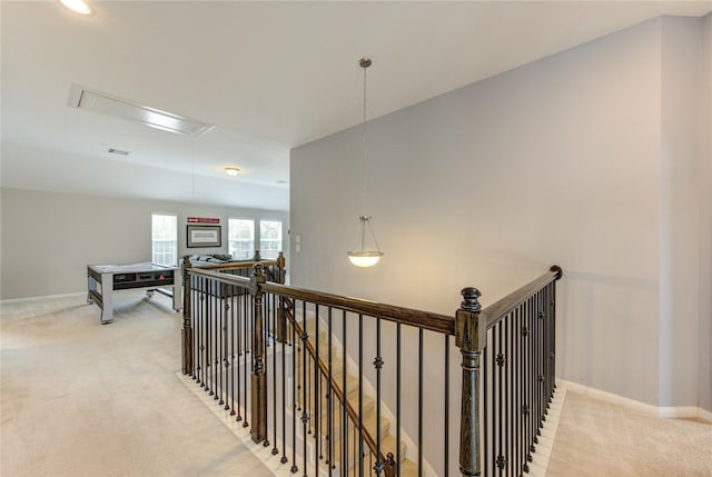 hall featuring baseboards, an upstairs landing, attic access, and light colored carpet