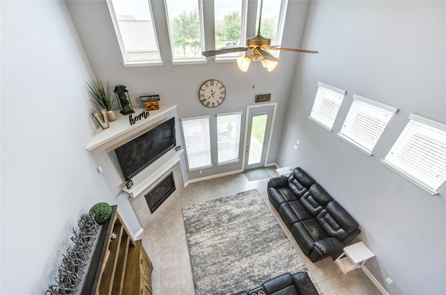 living room featuring a ceiling fan, tile patterned floors, plenty of natural light, and a towering ceiling
