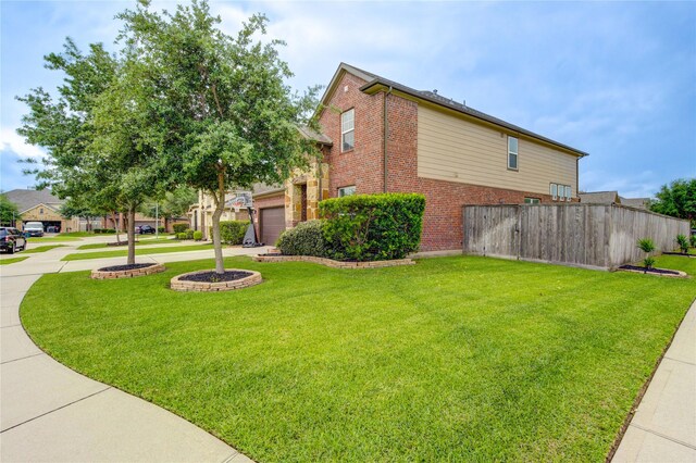 view of home's exterior with brick siding, a lawn, fence, and concrete driveway