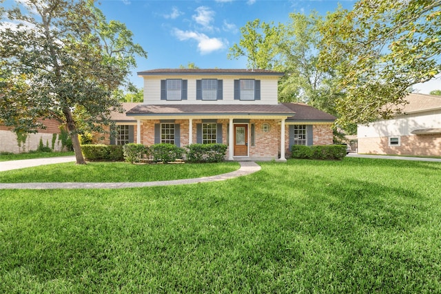 traditional-style home featuring roof with shingles, a front lawn, and brick siding