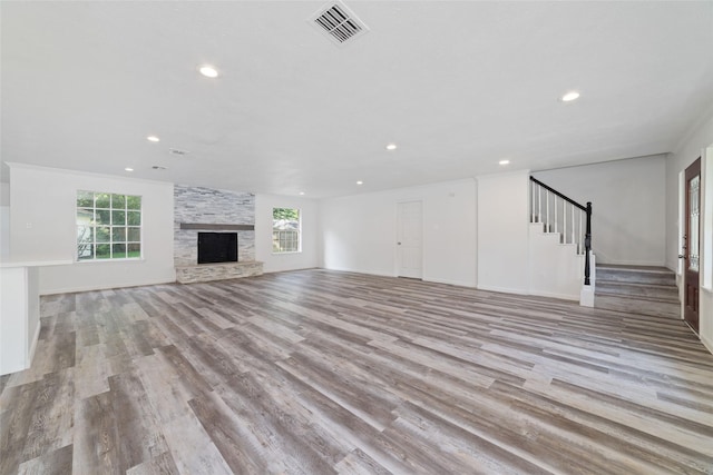 unfurnished living room with stairs, recessed lighting, a wealth of natural light, and light wood-type flooring