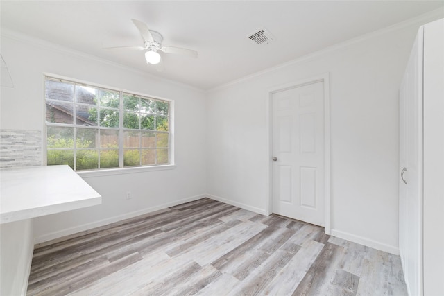 empty room with light wood-style floors, crown molding, ceiling fan, and visible vents