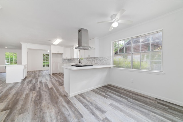 kitchen featuring light countertops, a peninsula, extractor fan, and a healthy amount of sunlight