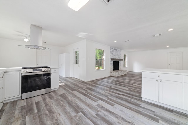 kitchen featuring gas stove, light wood-style flooring, open floor plan, island exhaust hood, and visible vents
