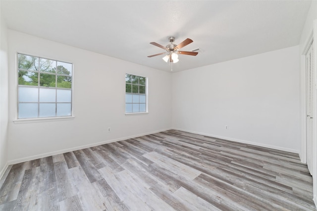 spare room featuring baseboards, plenty of natural light, a ceiling fan, and wood finished floors