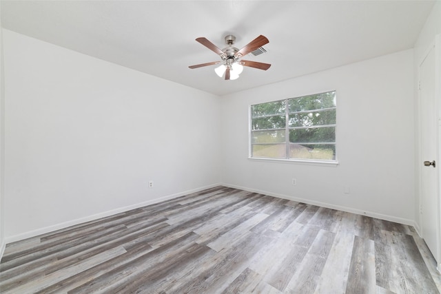 empty room with baseboards, ceiling fan, wood finished floors, and visible vents