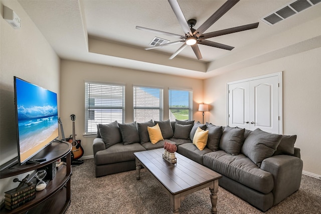 living room with carpet floors, a tray ceiling, and visible vents