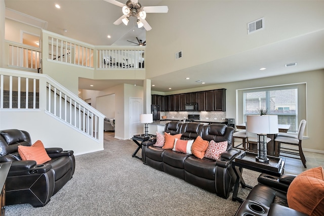 living room with a ceiling fan, visible vents, stairway, a high ceiling, and recessed lighting