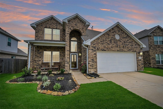 traditional home featuring fence, an attached garage, brick siding, a yard, and driveway