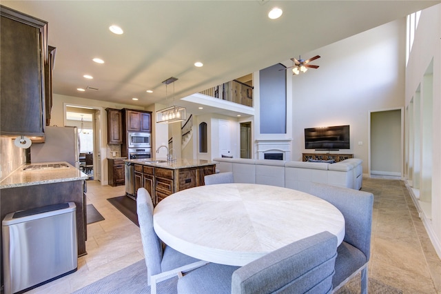 dining room featuring ceiling fan, a fireplace, recessed lighting, baseboards, and light tile patterned floors