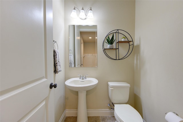 half bath featuring baseboards and toilet