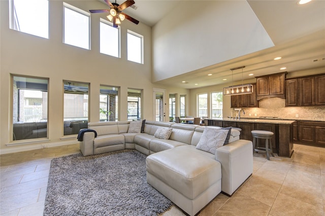 living area with recessed lighting, ceiling fan, light tile patterned flooring, and a towering ceiling
