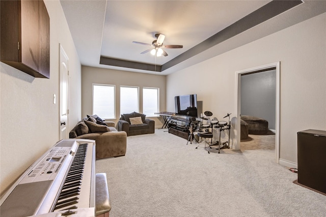 carpeted living area featuring baseboards, a raised ceiling, and ceiling fan