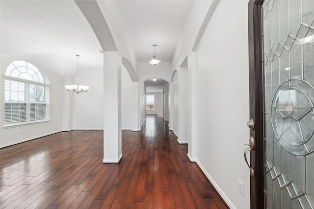 foyer entrance with arched walkways, baseboards, an inviting chandelier, and dark wood-style floors