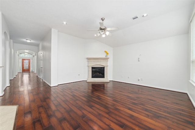 unfurnished living room featuring a ceiling fan, visible vents, arched walkways, dark wood finished floors, and baseboards
