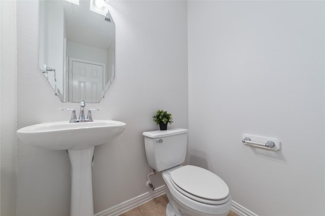 bathroom with a sink, toilet, tile patterned floors, baseboards, and visible vents