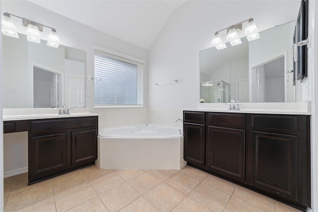 full bathroom with tile patterned flooring, two vanities, a shower stall, vaulted ceiling, and a bath