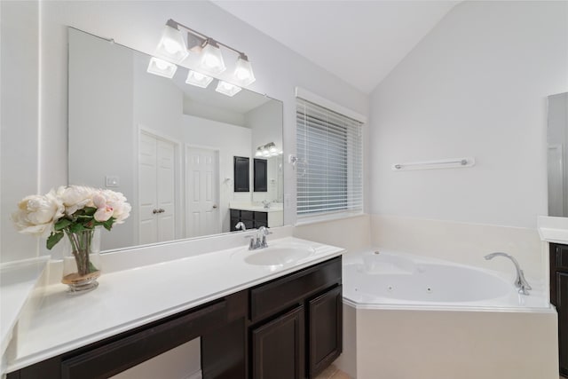 full bath with vanity, lofted ceiling, and a jetted tub
