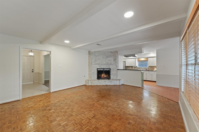 unfurnished living room with baseboards, a brick fireplace, and beam ceiling