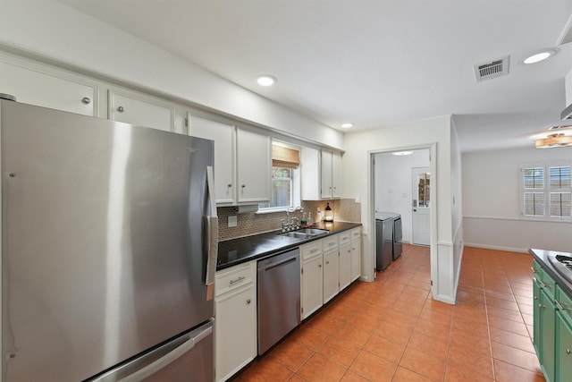 kitchen featuring backsplash, visible vents, washing machine and dryer, a sink, and stainless steel appliances