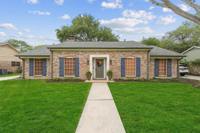 view of front of home featuring a chimney, a front lawn, and brick siding