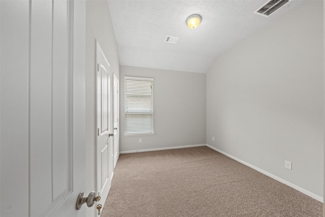 spare room with baseboards, carpet, vaulted ceiling, and visible vents