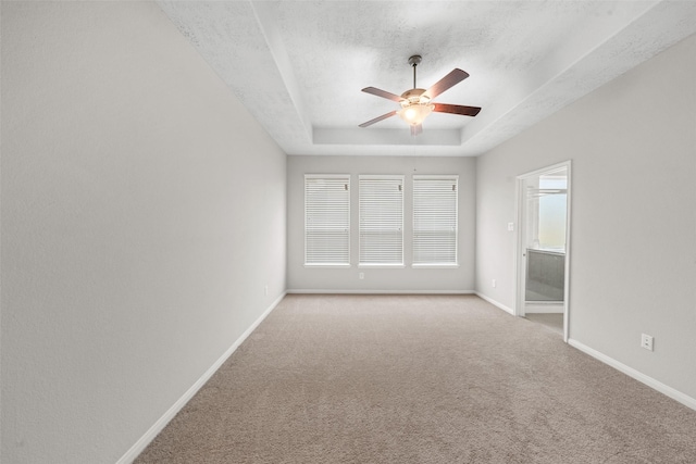 unfurnished bedroom with baseboards, a raised ceiling, a textured ceiling, and carpet