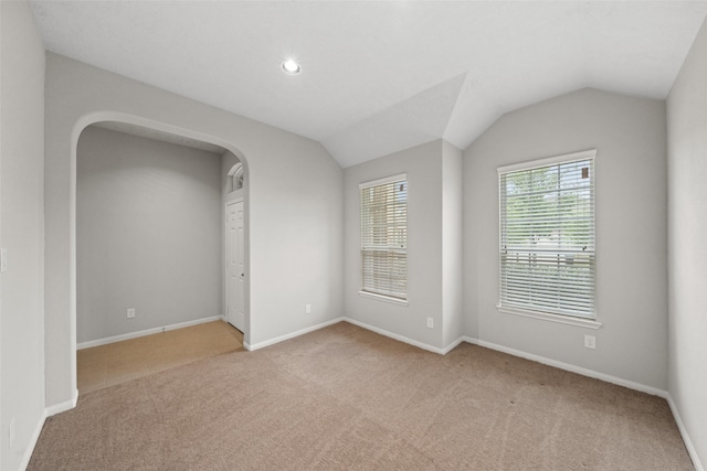 carpeted spare room featuring arched walkways, baseboards, vaulted ceiling, and recessed lighting