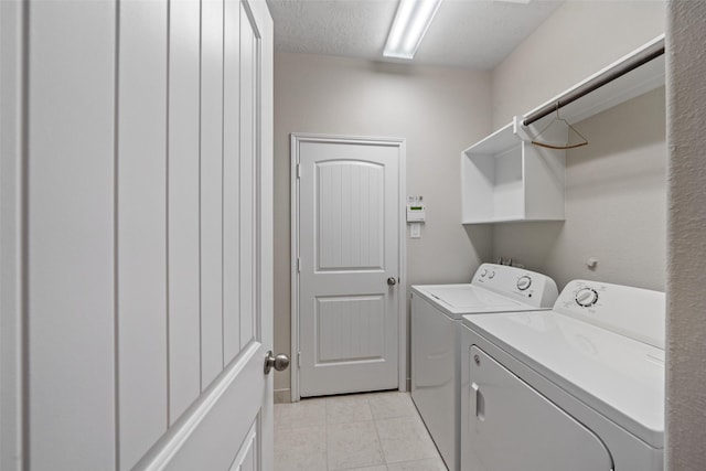 clothes washing area with laundry area, a textured ceiling, light tile patterned flooring, and washer and dryer