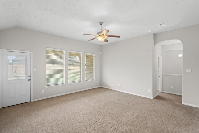 21310 Huron Bnd, Porter, TX 77365 - unfurnished living room featuring carpet floors, a ceiling fan, baseboards, arched walkways, and lofted ceiling