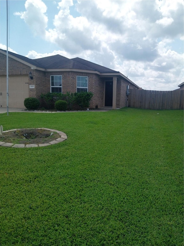 view of front facade featuring fence, an attached garage, a front yard, and brick siding