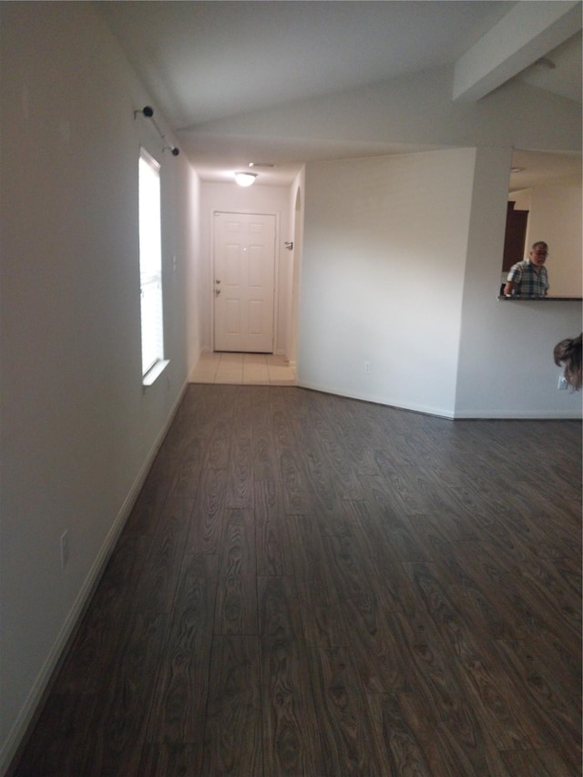 unfurnished room featuring baseboards, beamed ceiling, and wood finished floors