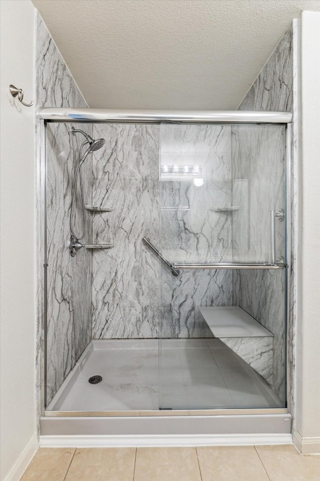 4910 Pacific Ridge Ln, Rosenberg, TX 77469 - bathroom featuring tile patterned flooring, a marble finish shower, baseboards, and a textured ceiling