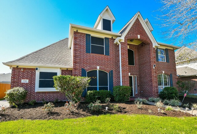 view of front facade featuring brick siding and a shingled roof