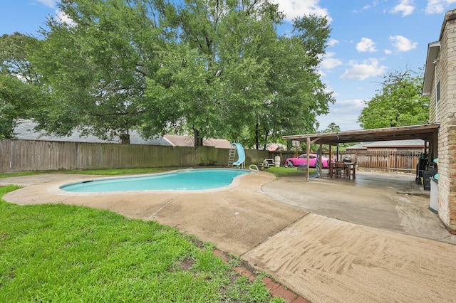 view of pool featuring a patio area, a fenced in pool, a fenced backyard, a yard, and a water slide