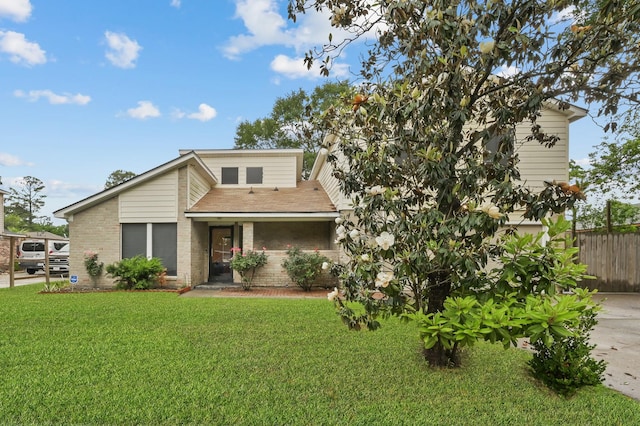 view of front of property with brick siding, a front lawn, and fence