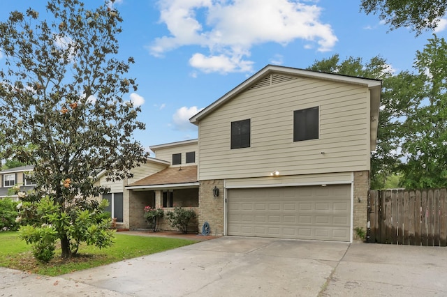traditional-style home with brick siding, a garage, fence, and concrete driveway