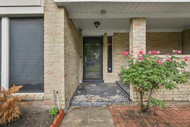 doorway to property with covered porch and brick siding